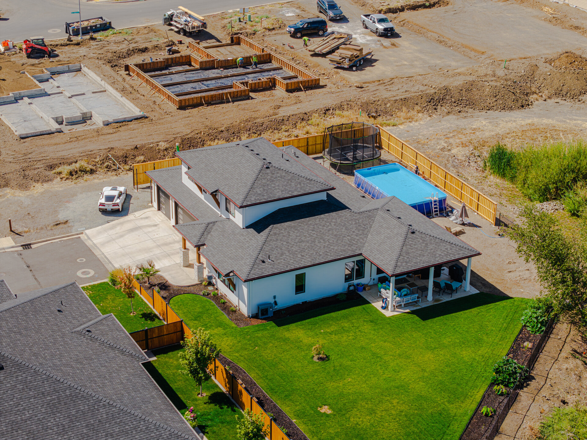 Aerial view of a finished home beside an active residential construction site